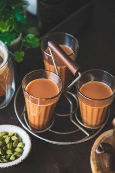 three glasses filled with liquid sitting on top of a table next to some nuts and spices