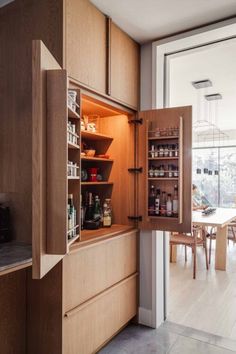 an open cabinet in the middle of a kitchen with lots of cupboards and shelves