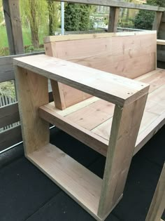 a bench made out of wood sitting on top of a black floor next to a wooden fence