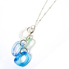 three blue and green necklaces hanging from a silver chain