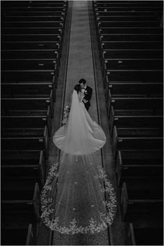 a bride and groom standing in front of pews at the end of a church