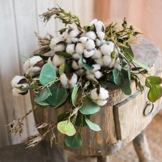 a wooden bucket filled with cotton and greenery