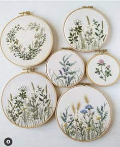 four cross stitch embroiderys with flowers and plants in them on a white table top