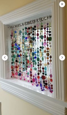 a window with many different colored beads hanging from it's side and on the wall