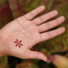 a person's hand with a small flower tattoo on it