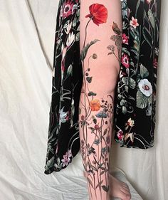 a woman's leg with flowers and leaves on it