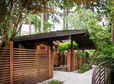 an outdoor area with wooden fences and trees in the background, along with a walkway that leads to a covered pavilion