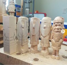 several carved wooden statues sitting on top of a workbench in a workshop area