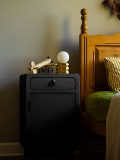 a small black cabinet sitting next to a bed