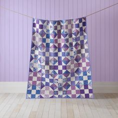 a purple and white quilt hanging on a clothes line in front of a purple wall