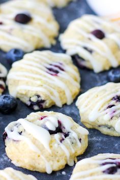 blueberry scones with icing and fresh berries on a baking sheet, ready to be eaten