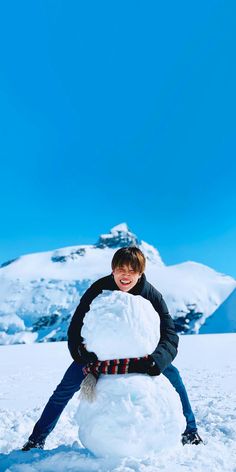 a young boy is building a snowman in the snow with his hands and legs