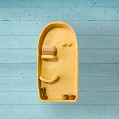 a yellow wall mounted toothbrush holder on a blue wooden wall with succulents