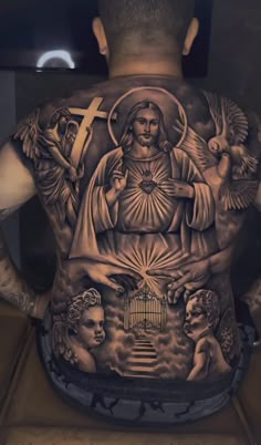 the back of a man's body with tattoos on it, including an image of jesus