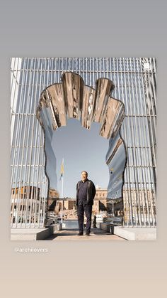 a man is standing in front of a large metal structure that looks like an arch