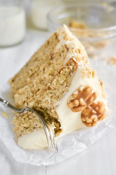 a piece of cake with white frosting and nuts on top is being held by a fork