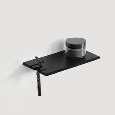 a black shelf with a jar on it and a pair of scissors next to it