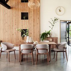 a dining room table with four chairs and a clock on the wall