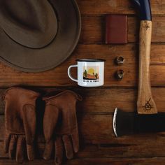 a hat, glove and mug sitting on top of a wooden table next to a pair of gloves