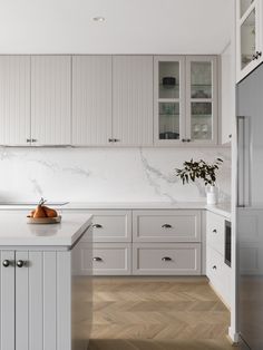 a large kitchen with white cabinets and marble counter tops, along with wooden flooring