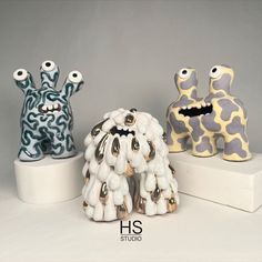 three ceramic figurines sitting on top of a white shelf next to each other