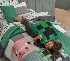 a woman laying on top of a bed covered in green and black quilts,