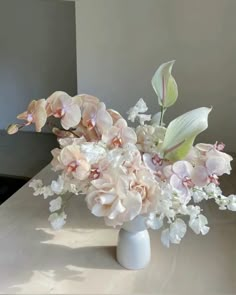 a white vase filled with flowers on top of a table