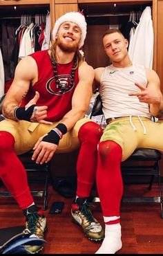 two men sitting next to each other in front of a closet full of sports gear