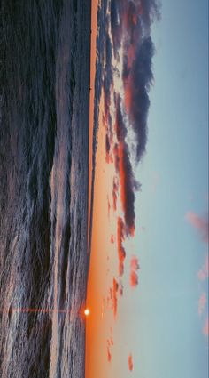 the sun is setting on an ocean shore