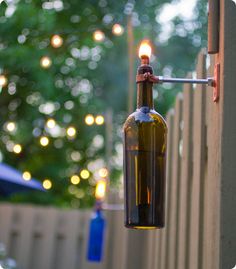 a wine bottle hanging from the side of a wooden fence with lights in the background