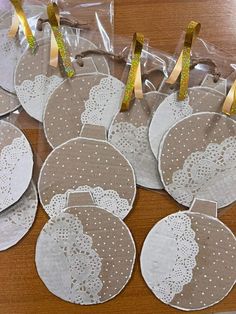 six lace doily christmas ornaments in plastic bags on a wooden table with gold ribbon