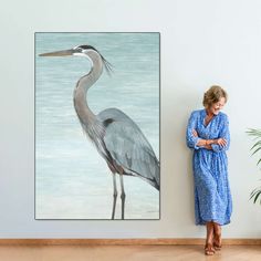 a woman standing next to a painting of a bird