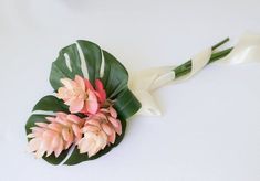 a bouquet of flowers on top of a white table with green leaves and pink tulips