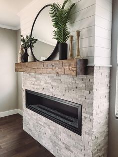 a white brick fireplace with a mirror and potted plant on it's mantle