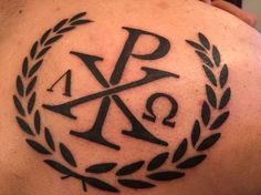 a tattoo on the back of a man's shoulder that has an ancient symbol in it