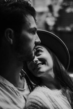 a black and white photo of a man and woman looking at each other while smiling