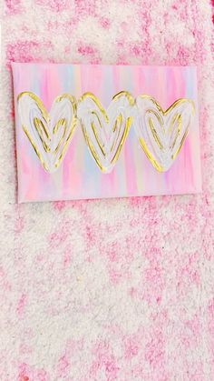 three heart shaped stickers sitting on top of a pink and white towel with gold foil