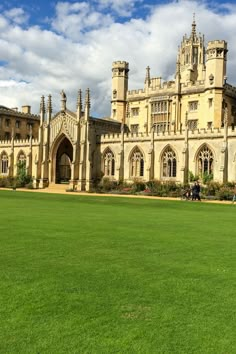 a large building with lots of windows on top of green grass and people walking around