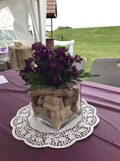 there is a vase with flowers and wine corks in it on top of a table