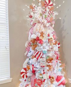 a white christmas tree decorated with red and white ribbons, teddy bears, snowflakes and other decorations