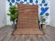 a large rug sitting on top of a wooden floor next to a potted plant