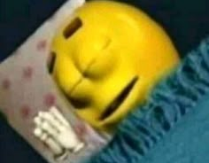 a yellow smiley face laying on top of a blue blanket next to a remote control