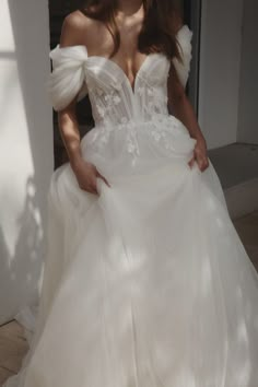 a woman in a white wedding dress posing for the camera with her hands on her hips