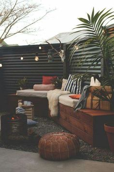 an outdoor living area with couches, tables and potted plants on the ground