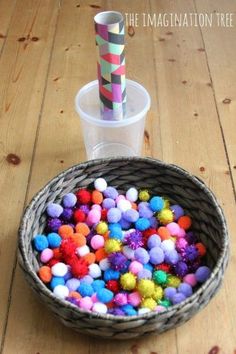 a basket filled with pom - poms next to a plastic cup on a wooden table