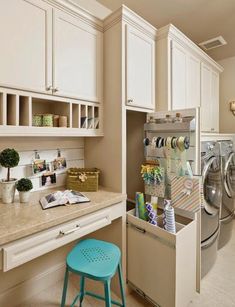 a washer and dryer in a room with white cabinets, counter tops and stools