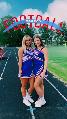 two cheerleaders pose for a photo in front of the football stadium sign that says football season