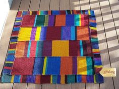 a multicolored blanket sitting on top of a wooden floor next to a sign