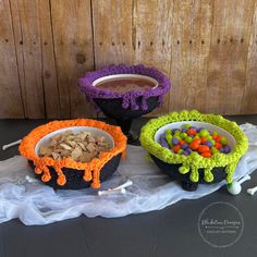 three crocheted bowls with candy and candies in them sitting on a table