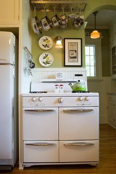 a white stove top oven sitting inside of a kitchen next to a wall mounted pot rack